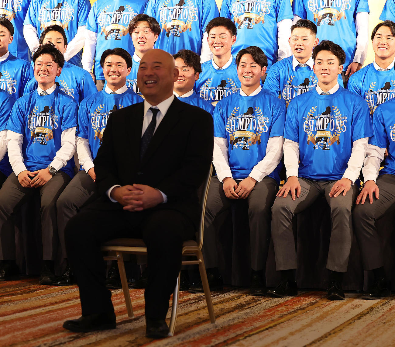 青学大祝賀会で一人ステージの前のイスに座り記念撮影に臨む安藤監督（手前）に笑顔を見せる阪神ドラフト1位下村（同右から2人目）、広島ドラフト1位常広（同右端）ら（撮影・足立雅史）
