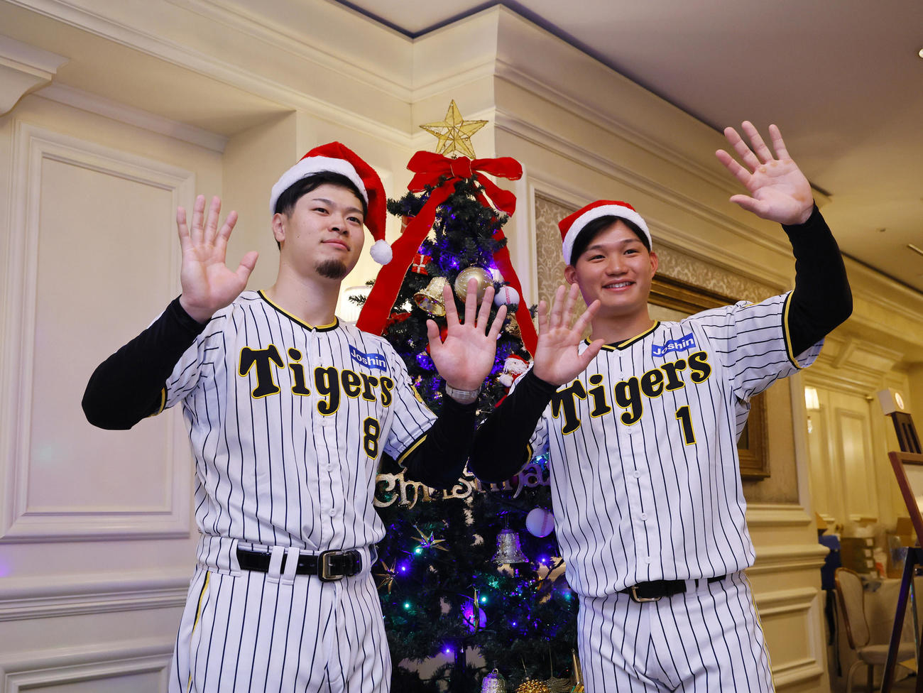 ファンクラブイベントの「クリスマスパーティー」でツリーの前で写真に納まる阪神佐藤輝（左）と森下（撮影・藤尾明華）