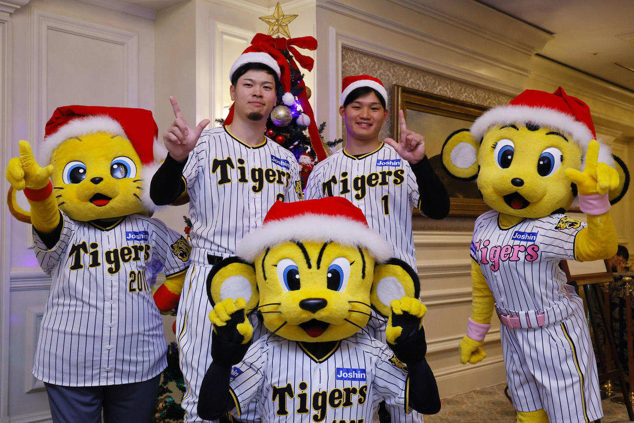ファンクラブイベントの「クリスマスパーティー」でツリーの前で写真に納まる阪神佐藤輝（左）と森下（撮影・藤尾明華）