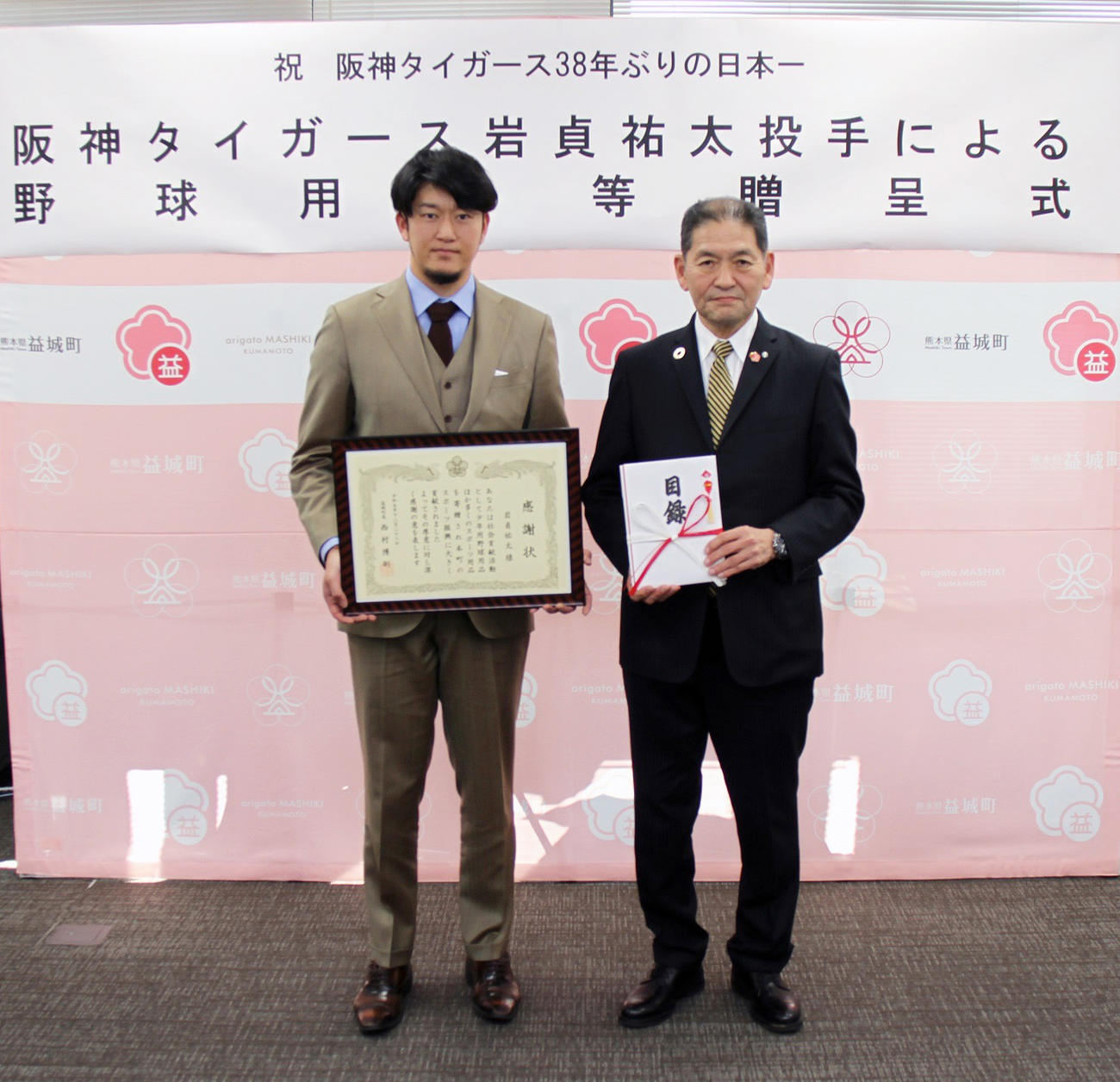 益城町役場で阪神岩貞による野球用品等贈呈式が行われ、西村町長（右）から感謝状を受け取る岩貞（熊本県益城町提供）