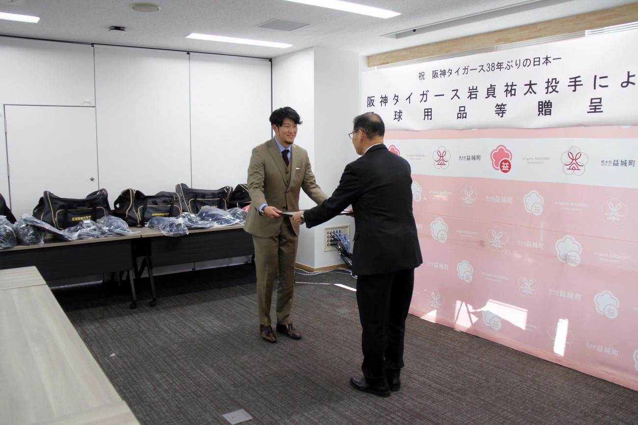 益城町役場で阪神岩貞による野球用品等贈呈式が行われ、西村町長（右）から感謝状を受け取る岩貞（熊本県益城町提供）