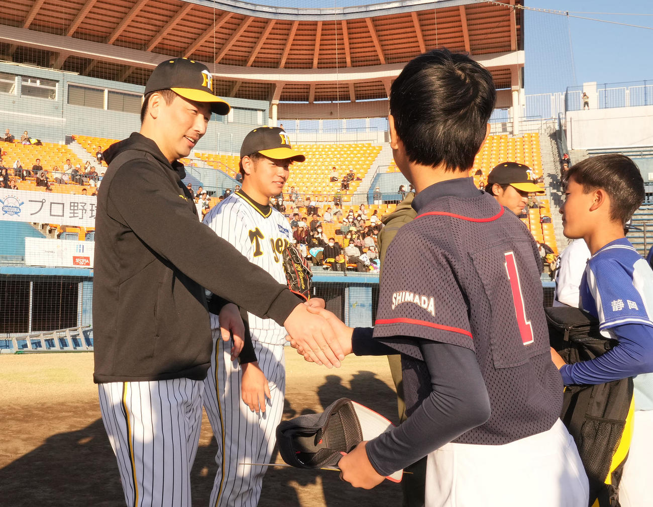 野球教室に参加しサイン入り帽子のプレゼントを渡し握手を交わす岩崎（左）（撮影・森本幸一）
