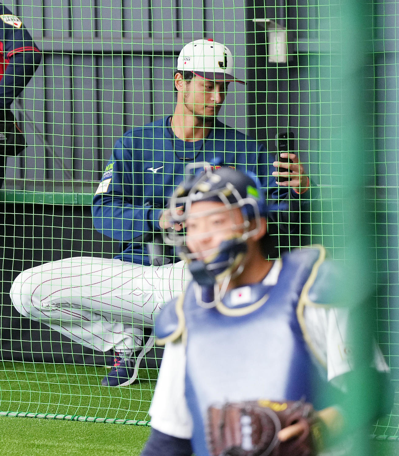 2月、ブルペンで投球練習をする投手陣を携帯で撮影するダルビッシュ