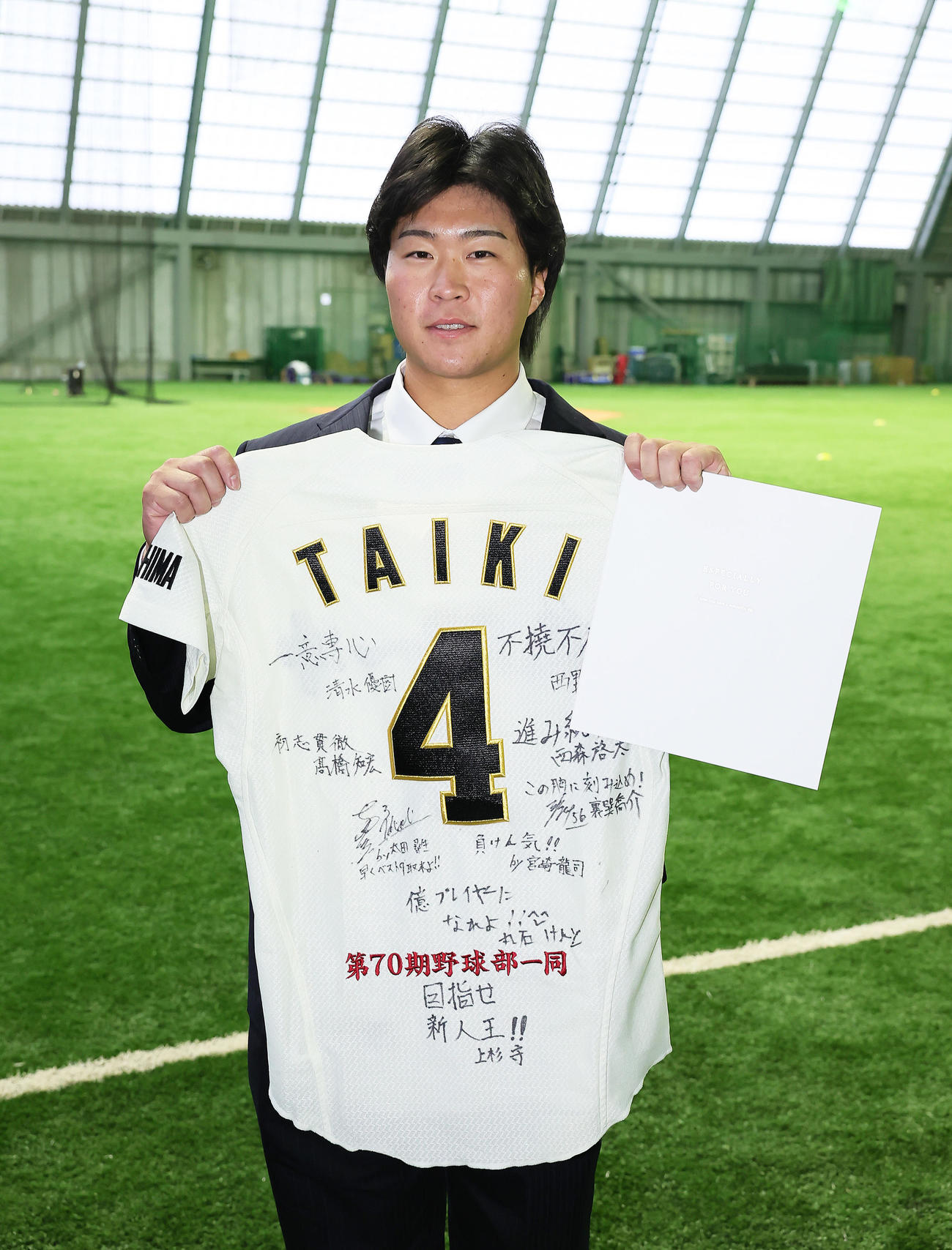 DeNAドラフト4位石上は青星寮に入寮し、寄せ書きとユニホームを手に笑顔（撮影・足立雅史）日