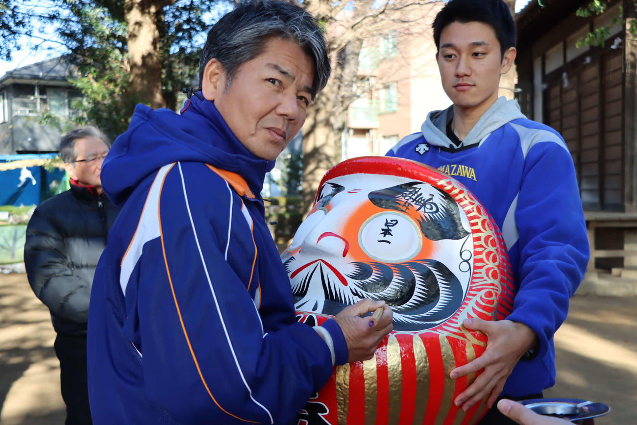 グラウンド近くの神明神社で必勝祈願し、日本一を祈願しダルマの目入れを行う駒大・大倉監督（駒大野球部提供）