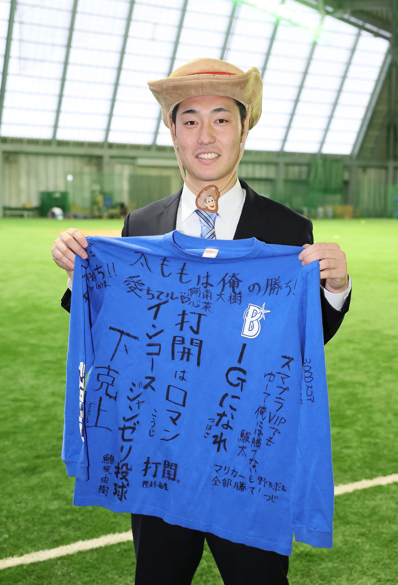 DeNA育成4位庄司は青星寮に入寮し、自身に似ているというウッディの姿で寄せ書きTシャツを手に笑顔（撮影・足立雅史）