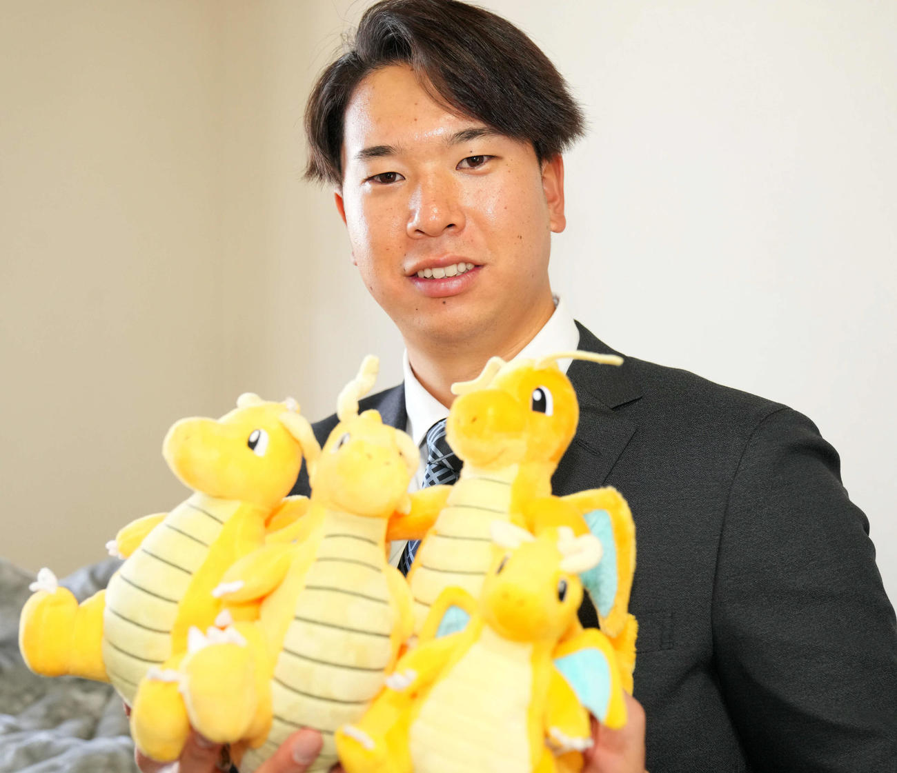 似てるとよく言われるポケモンのカイリューのぬいぐるみを手に笑顔を見せるロッテドラフト1位の明大・上田（撮影・横山健太）