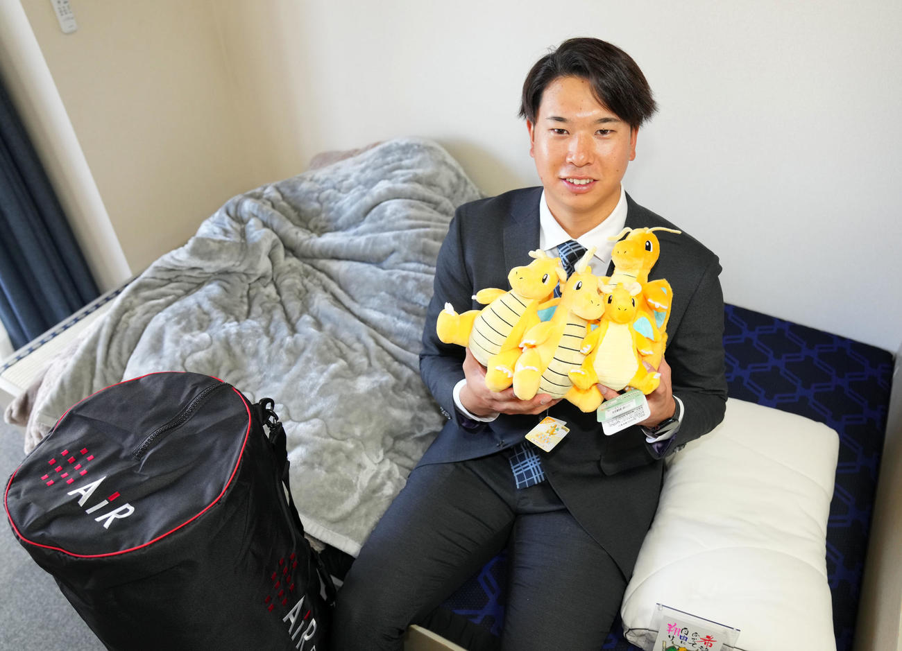 似てるとよく言われるポケモンのカイリューのぬいぐるみを手に笑顔を見せるロッテドラフト1位の明大・上田（撮影・横山健太）