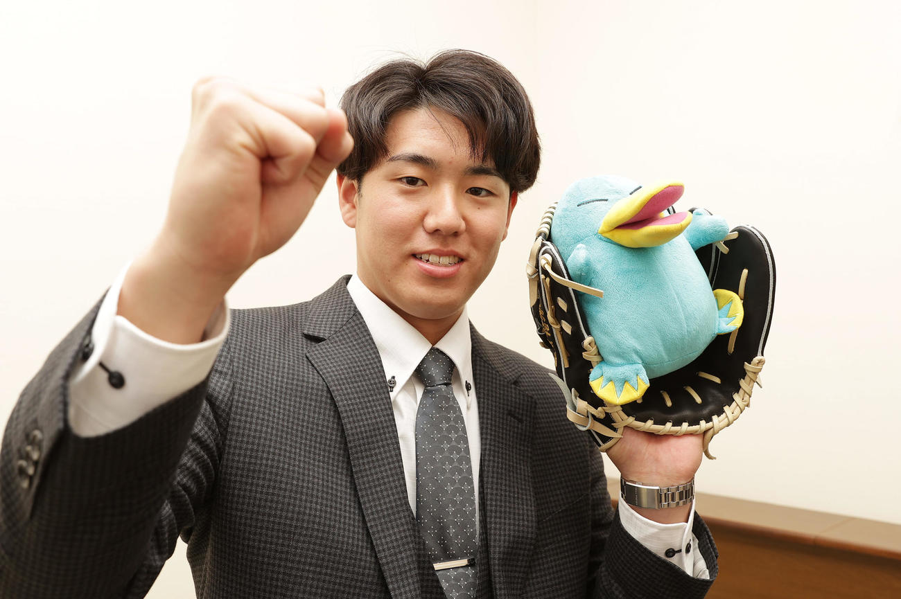 入寮し持ち込んだICOCAマスコットキャラクターのぬいぐるみとグラブを手にガッツポーズする阪神ドラフト5位の石黒（撮影・前田充）