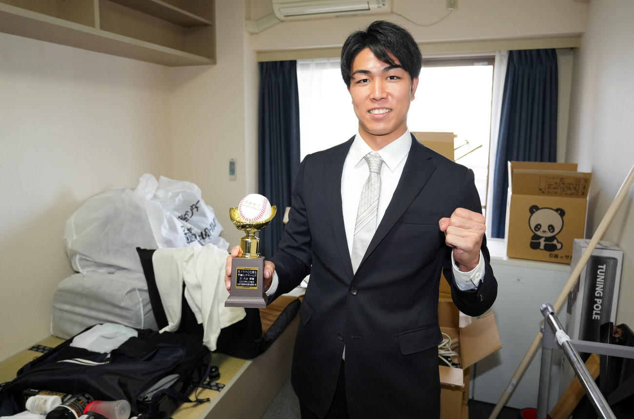 入寮に持参した中学生時代の同級生からプレゼントされたトロフィーを手に笑顔をみせるロッテドラフト2位の日本海L富山・大谷（撮影・横山健太）