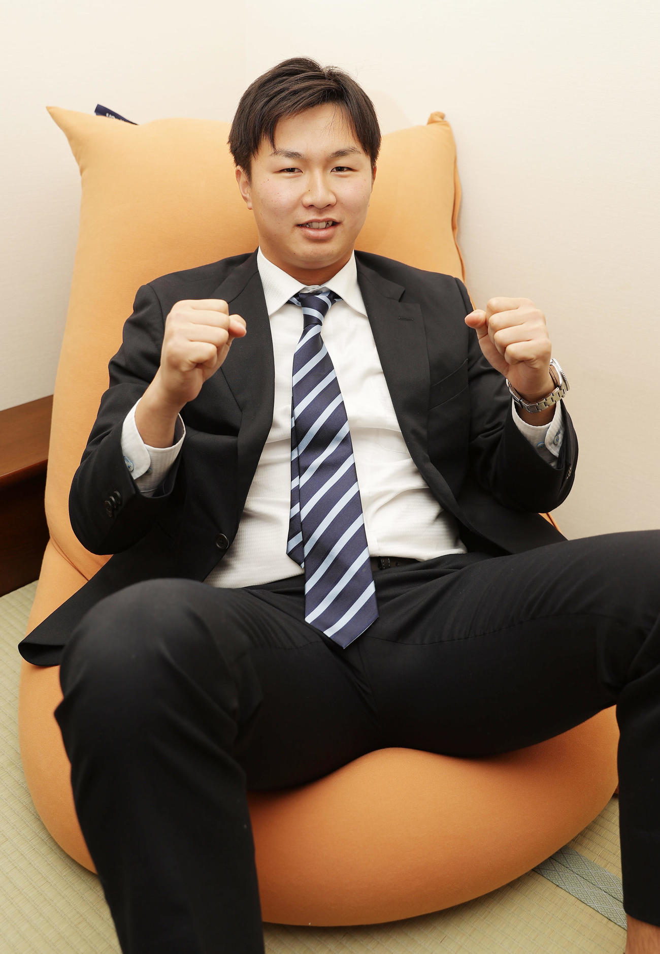 入寮し持ち込んだ愛用のクッションに腰掛けガッツポーズする阪神津田（撮影・前田充）