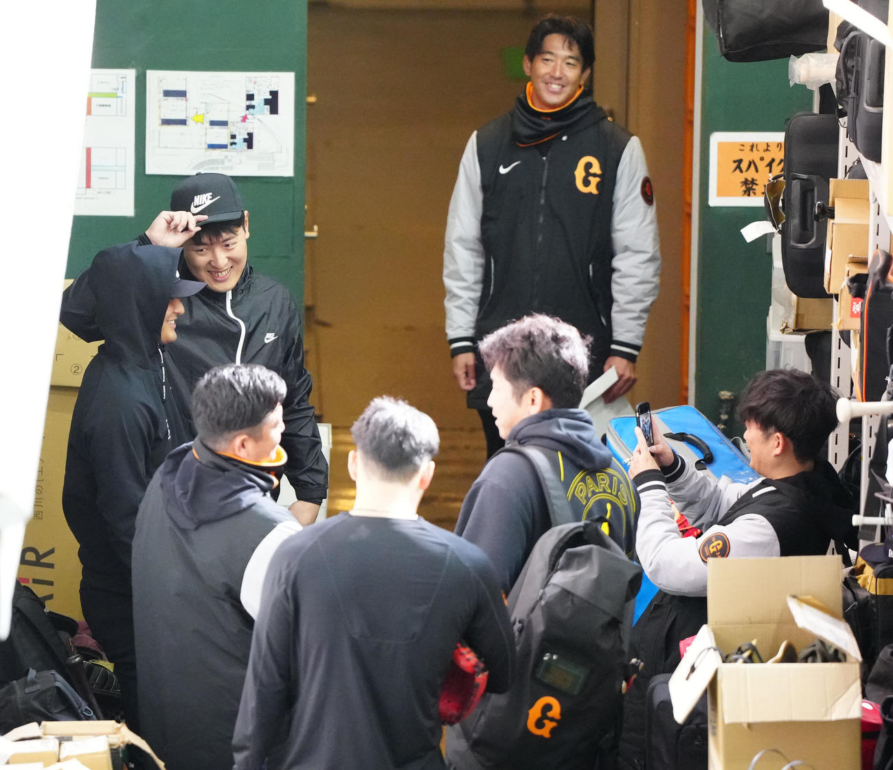 自主トレ後、記念撮影中、巨人吉川（左端）を見つめる岡本和（撮影・江口和貴）