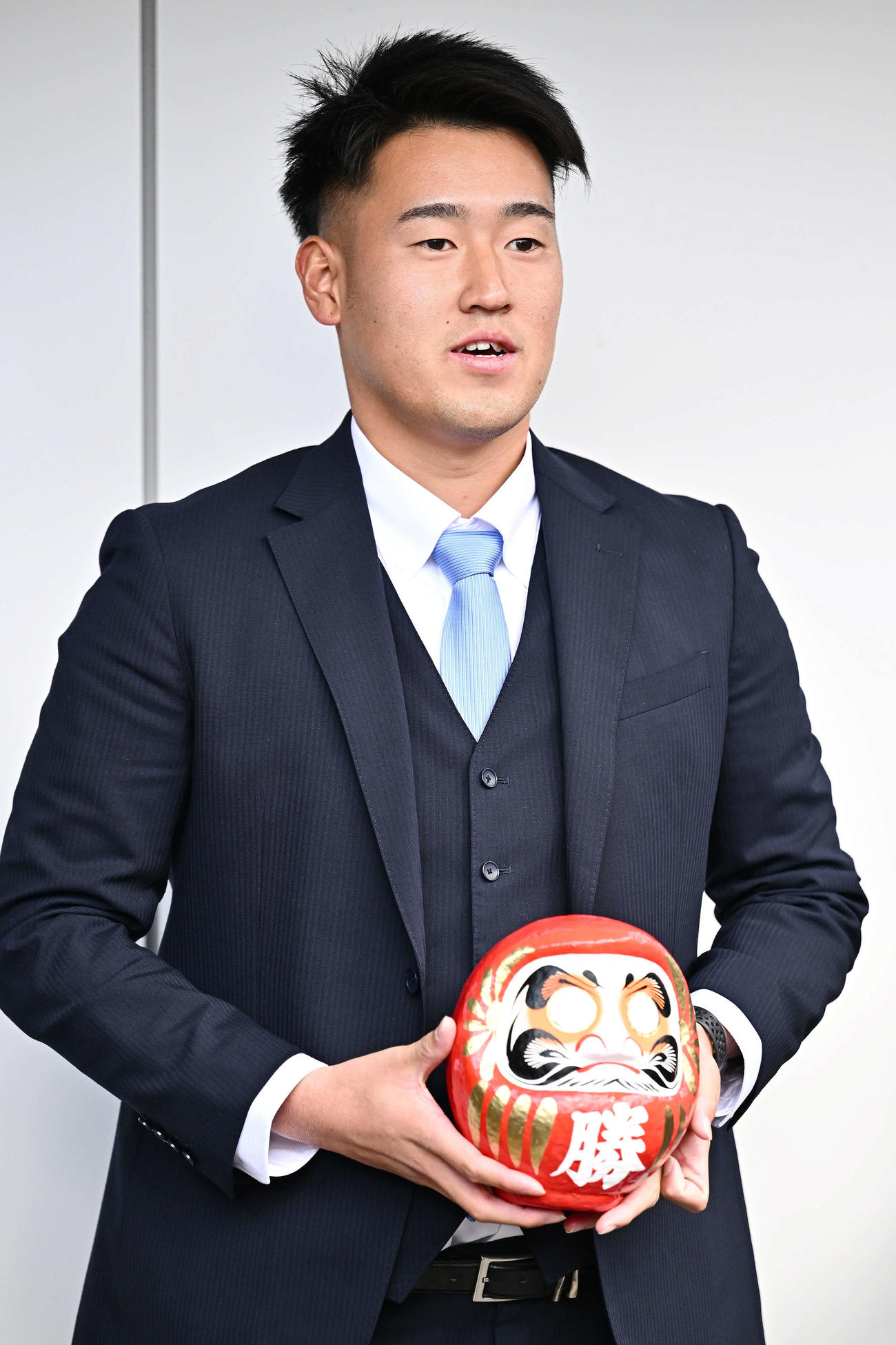 入寮する西武ドラフト2位の大商大・上田は、持ち込んだだるまを手に取材を受ける（撮影・滝沢徹郎）