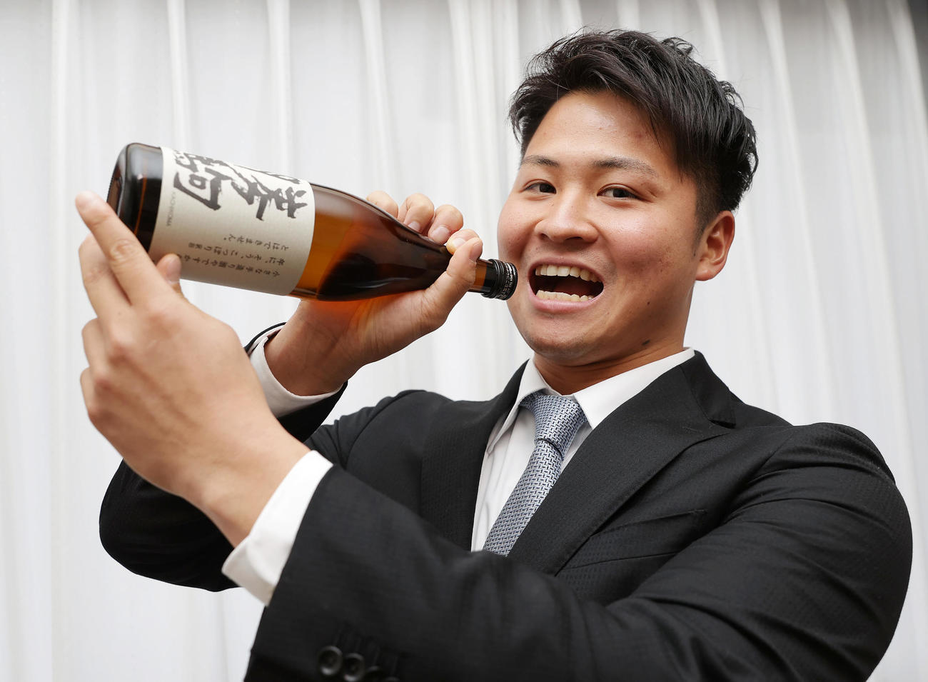 入寮し持ち込んだ地元の地酒を飲むポーズをとる阪神育成1位の松原（撮影・前田充）