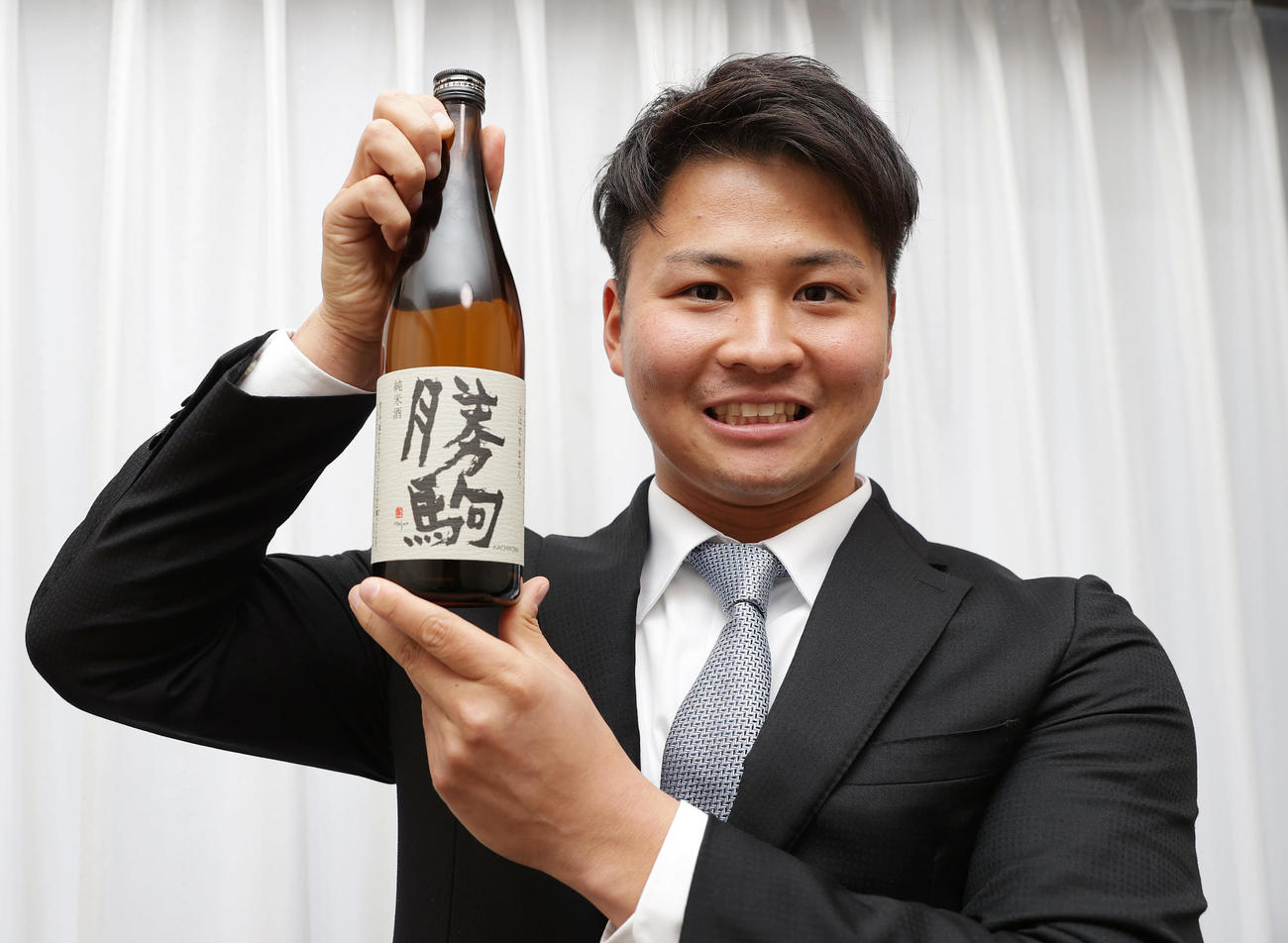 入寮し持ち込んだ地元の地酒を手に笑顔を見せる阪神育成1位の松原（撮影・前田充）