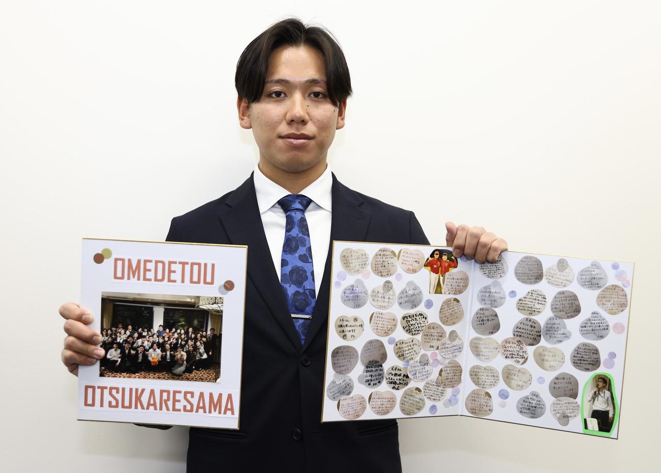 入寮し社会人時代の同僚から贈られた色紙を手に写真に納まる巨人ドラフト5位の又木（撮影・垰建太）