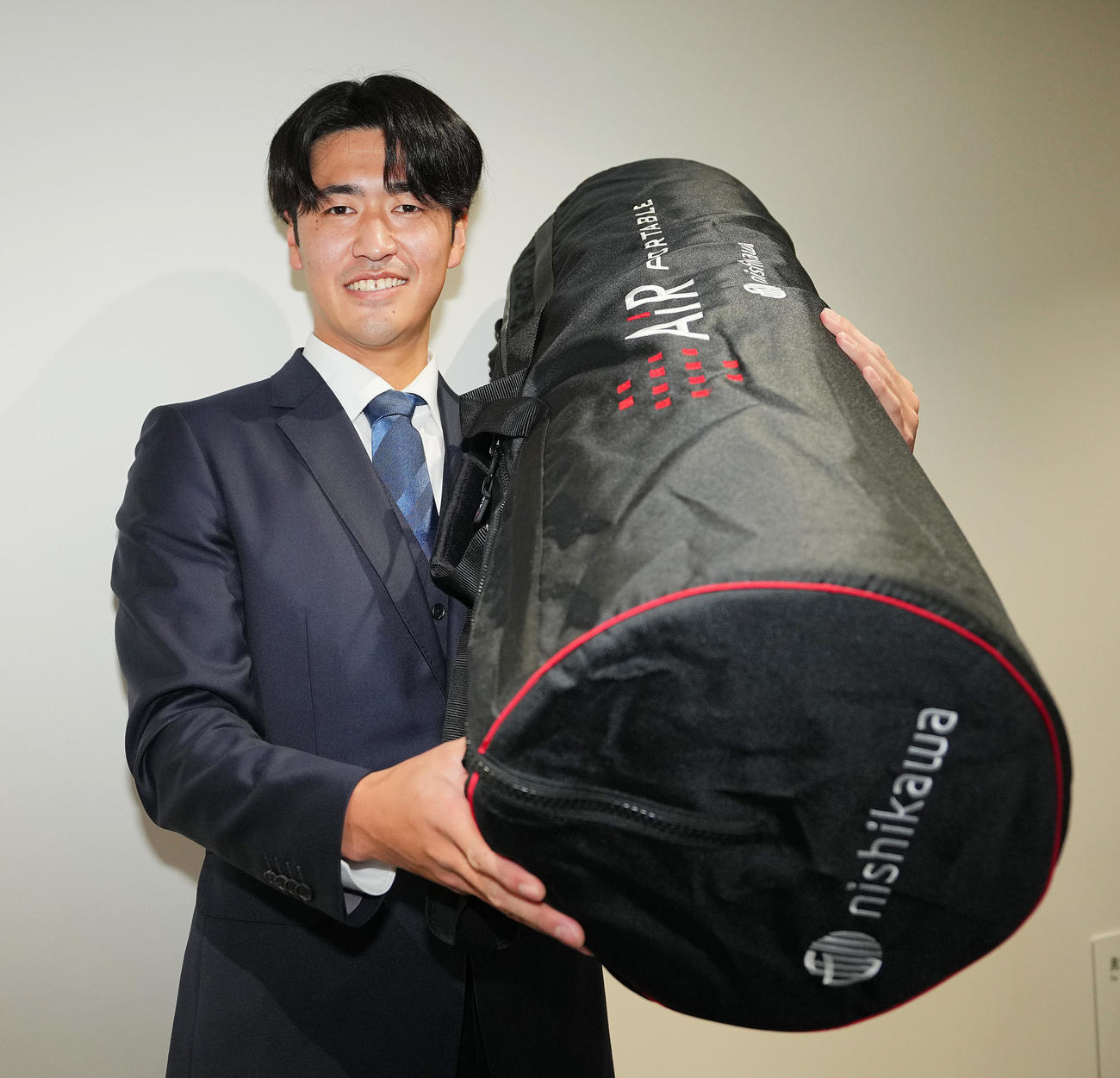入寮し持ち込んだマットレスを手に写真に納まる巨人1位西舘（撮影・垰建太）