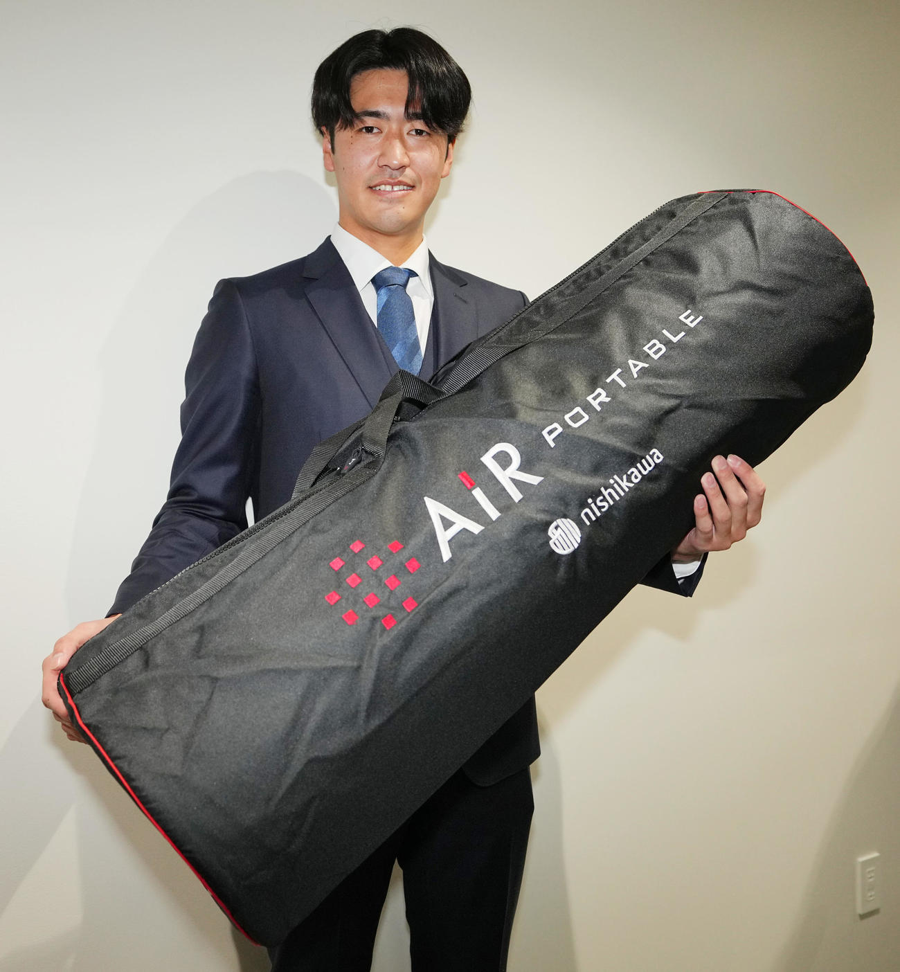 入寮し持ち込んだマットレスを手に写真に納まる巨人1位西舘（撮影・垰建太）
