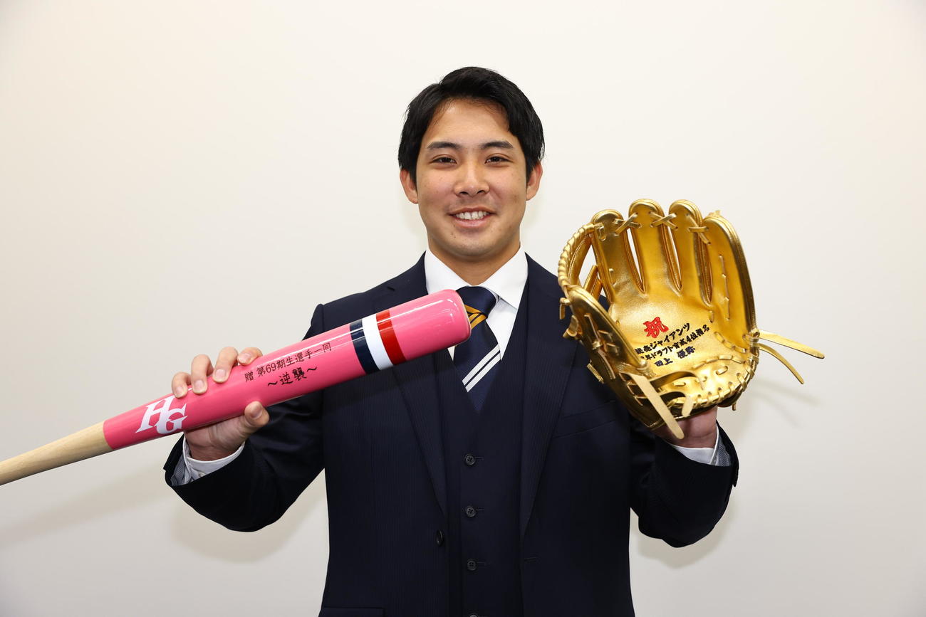入寮し日大藤沢の仲間たちから贈られたチームカラーのバットと金のグラブを手に写真に納まる巨人育成4位田上（撮影・垰建太）