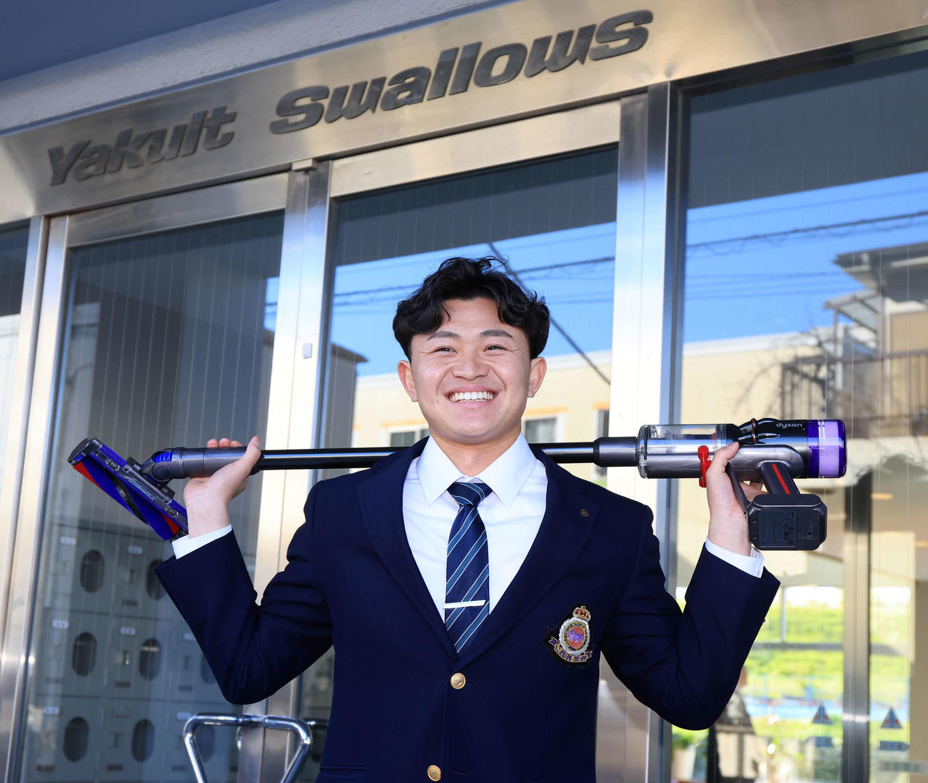 ヤクルト選手寮に入寮したドラフト3位の石原は、ダイソンの掃除機を背負って笑顔（撮影・浅見桂子）