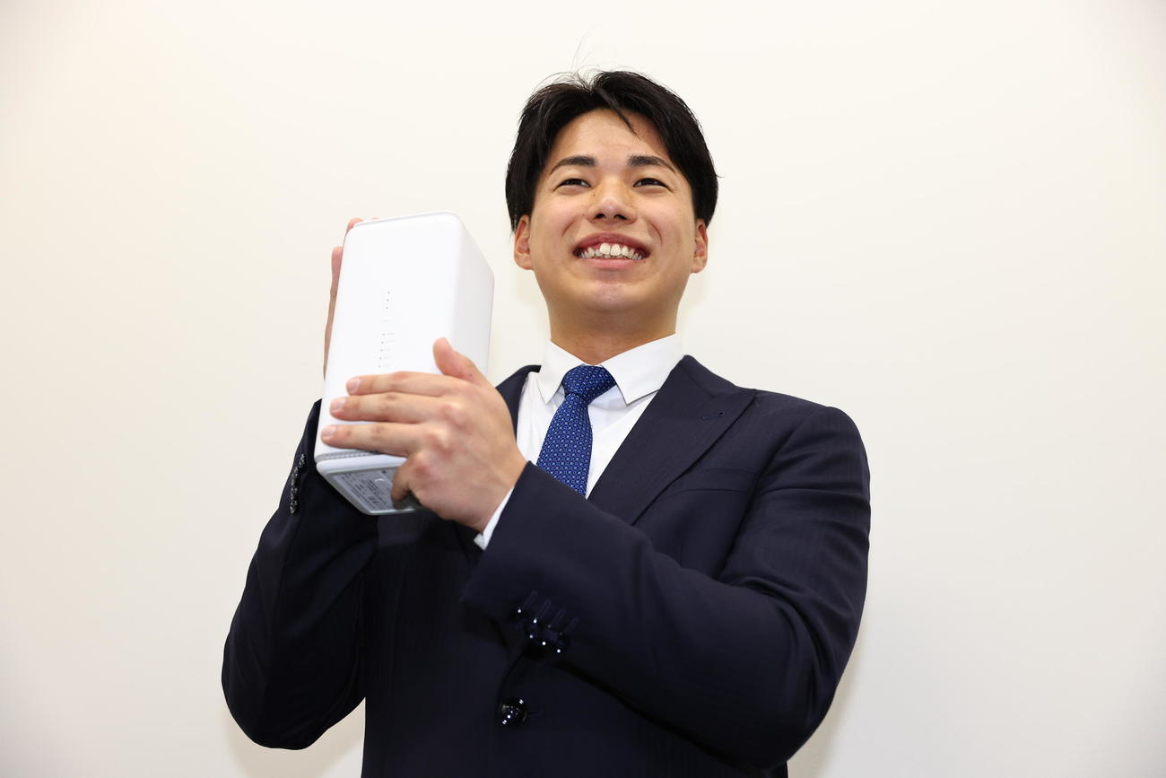 入寮した巨人育成1位三浦は持ち込んだWiーFiを手に写真に納まる（撮影・垰建太）
