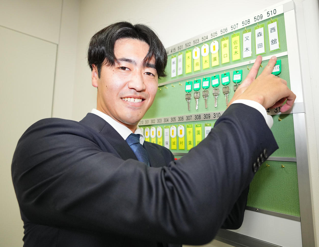 入寮した巨人1位西舘は自分の名札を指さし笑顔を見せる（撮影・垰建太）