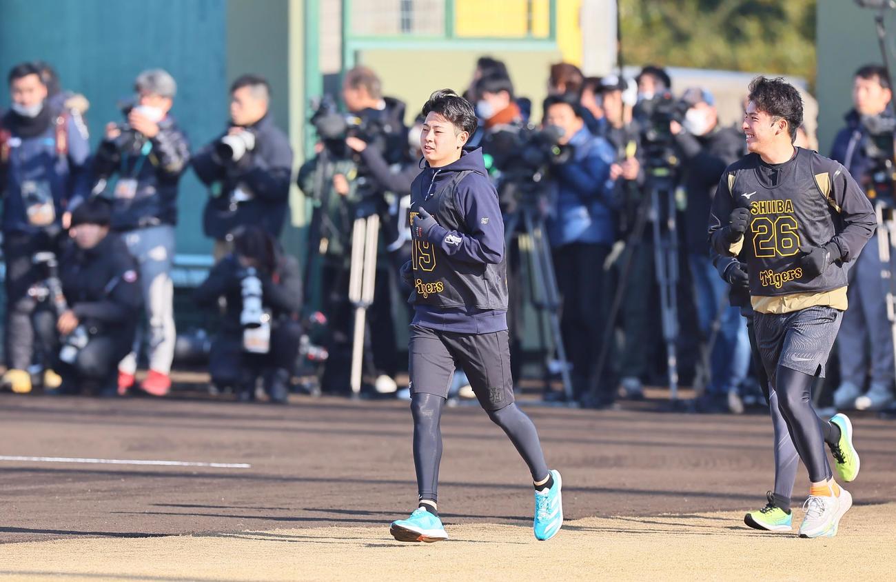 阪神ドラ1の下村（中央）は大勢の報道陣を背にグランド入りする（撮影・上田博志）
