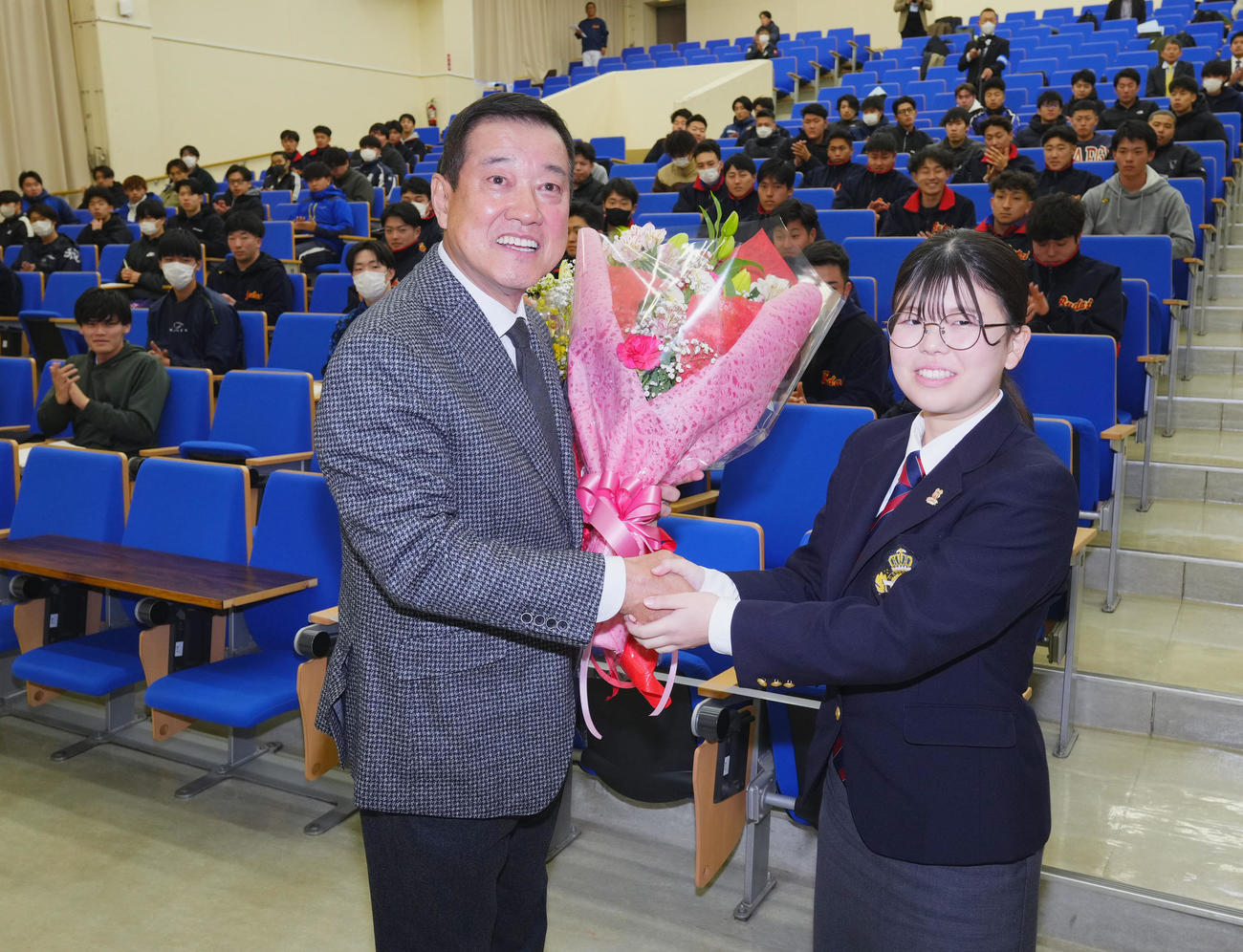 国際武道大学で講義をした原オーナー付特別顧問（左）は、生徒から花束を受け取り笑顔を見せる（撮影・菅敏）
