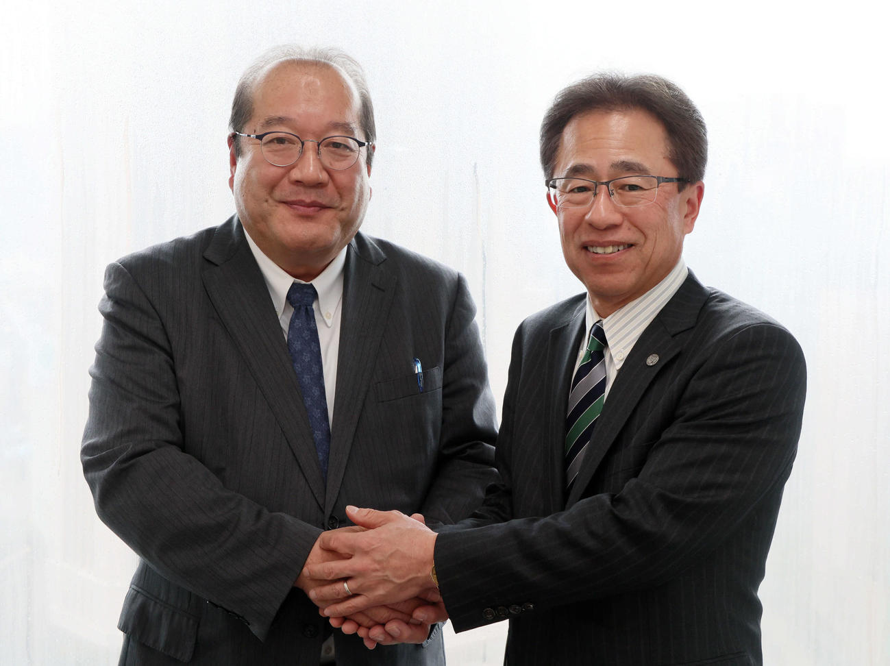 本社を訪れた阪神粟井球団社長（右）は日刊スポーツ新聞西日本の橘社長と笑顔で握手（撮影・加藤哉）