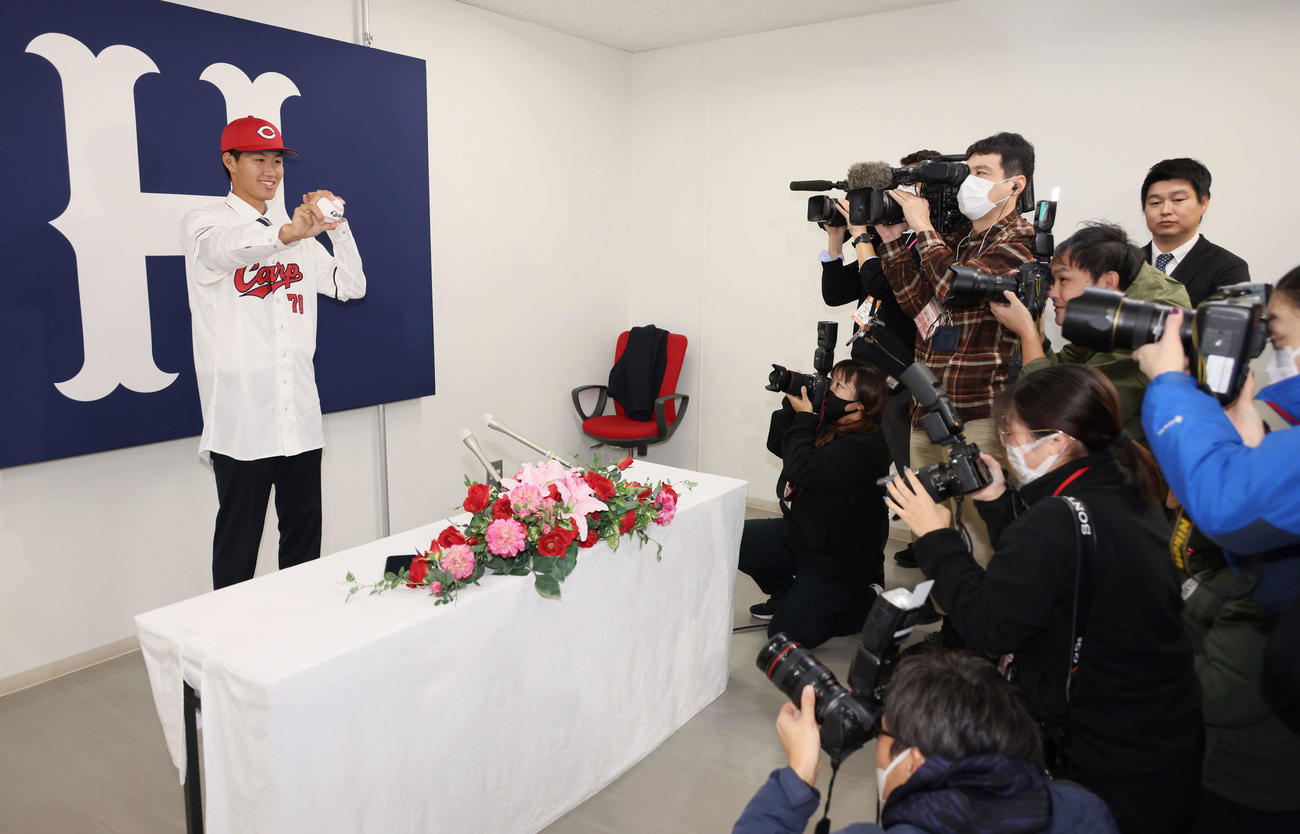 西川の人的補償でオリックスから広島に移籍、入団会見で広島のユニホームに袖を通し、ポーズを決める日高（撮影・加藤孝規）