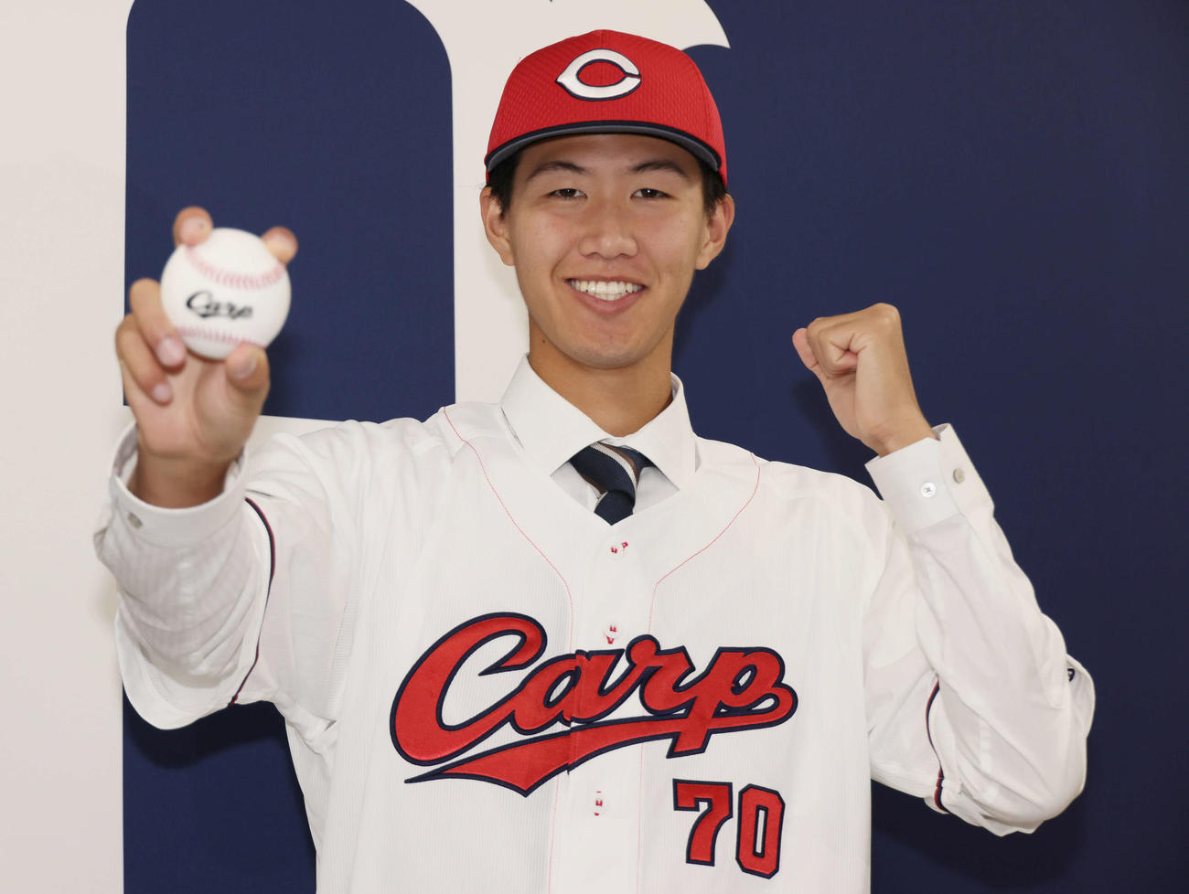 西川の人的補償でオリックスから広島に移籍、入団会見で広島のユニホームに袖を通し、ポーズを決める日高（撮影・加藤孝規）