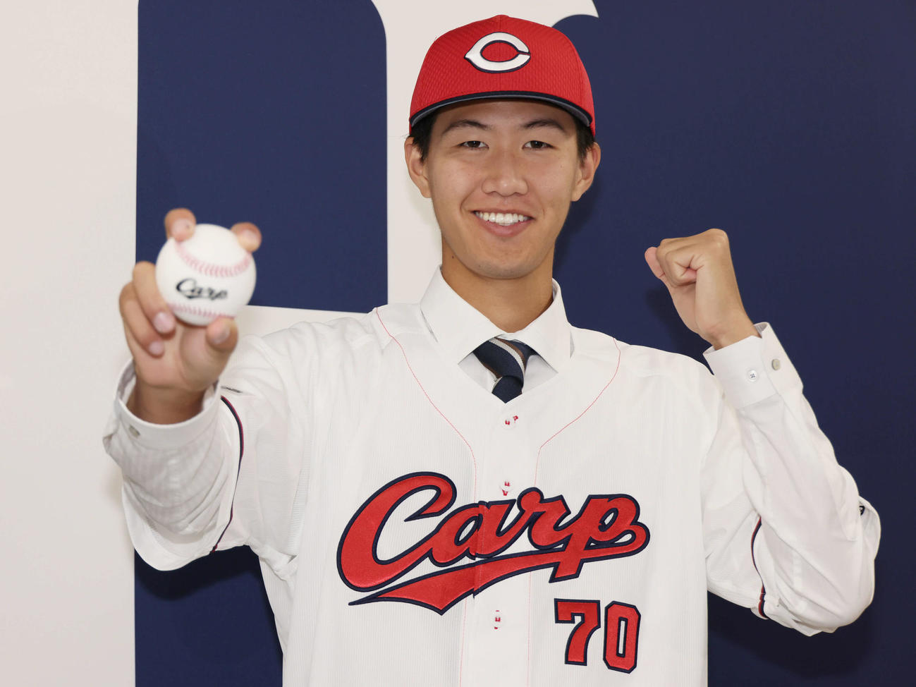 西川の人的補償でオリックスから広島に移籍、入団会見で広島のユニホームに袖を通し、ポーズを決める日高（撮影・加藤孝規）