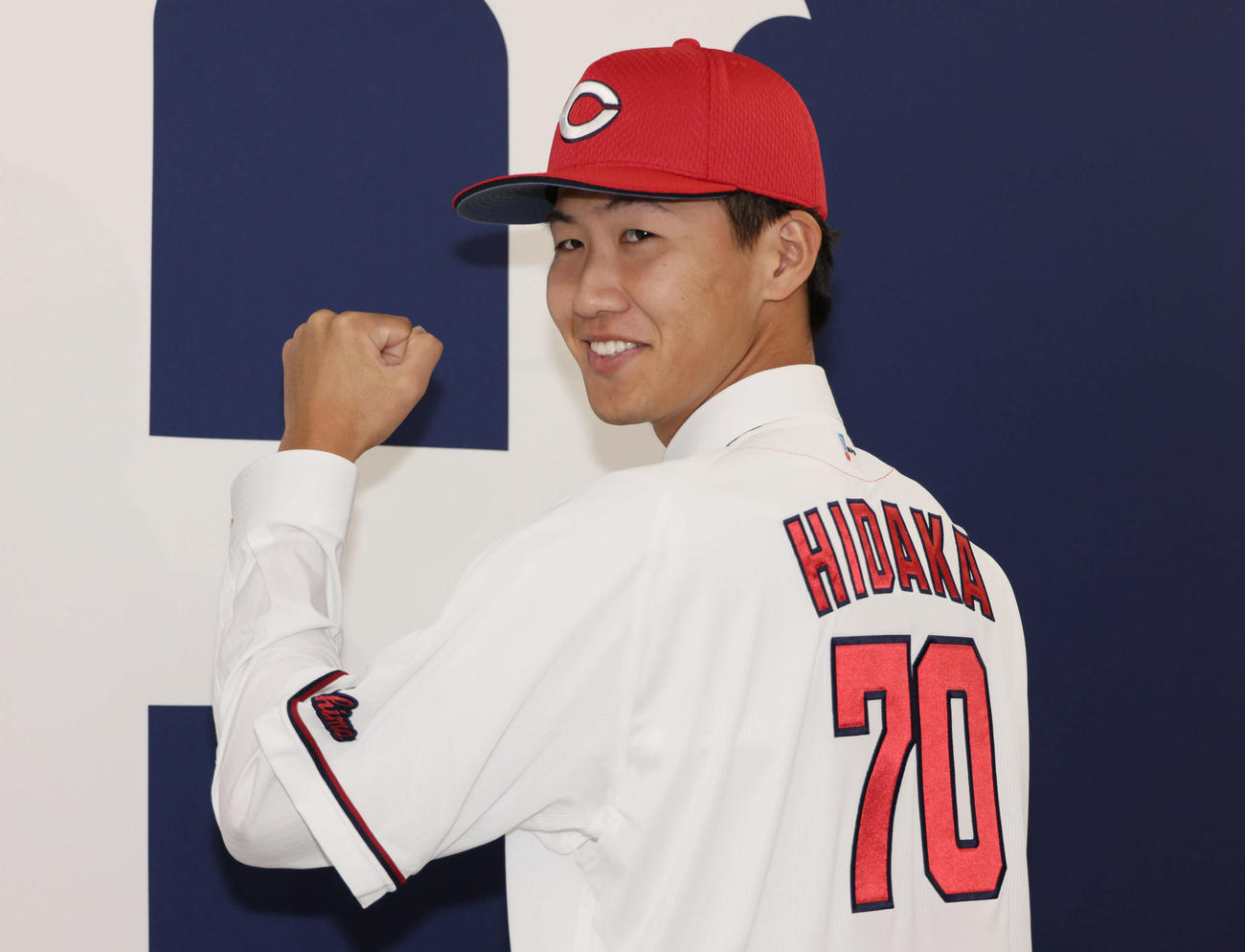 西川の人的補償でオリックスから広島に移籍、入団会見で広島のユニホームに袖を通し、ポーズを決める日高（撮影・加藤孝規）