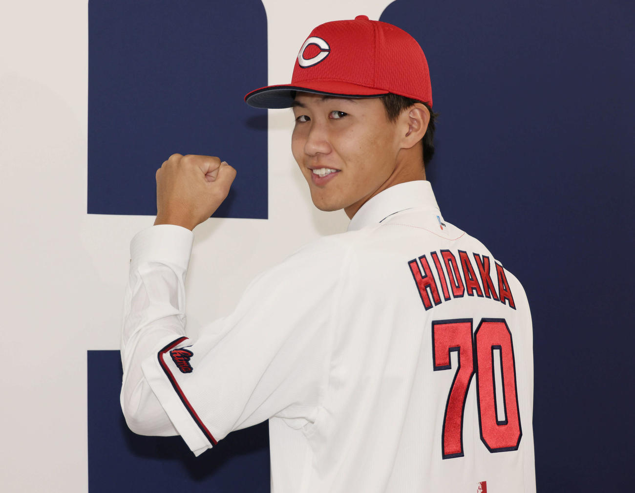 西川の人的補償でオリックスから広島に移籍、入団会見で広島のユニホームに袖を通し、ポーズを決める日高（撮影・加藤孝規）