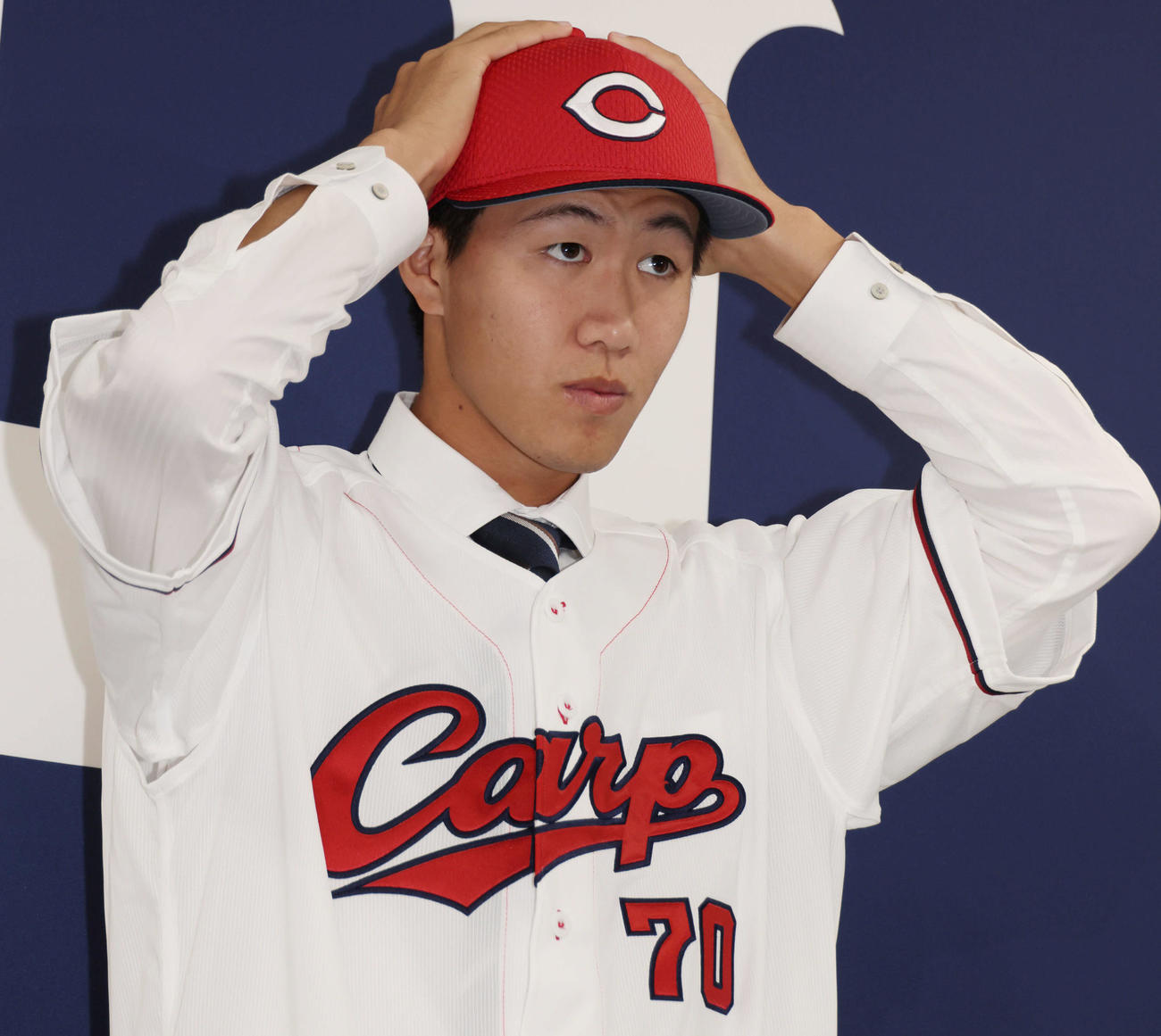 西川の人的補償でオリックスから広島に移籍、入団会見で広島のユニホームに袖を通し、ポーズを決める日高（撮影・加藤孝規）