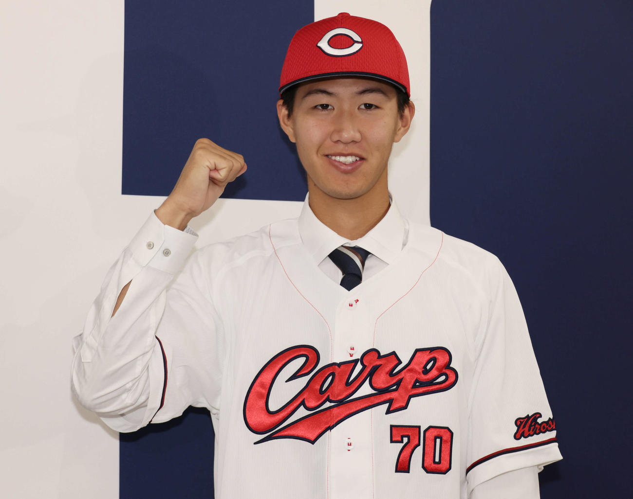 西川の人的補償でオリックスから広島に移籍、入団会見で広島のユニホームに袖を通し、ポーズを決める日高（撮影・加藤孝規）