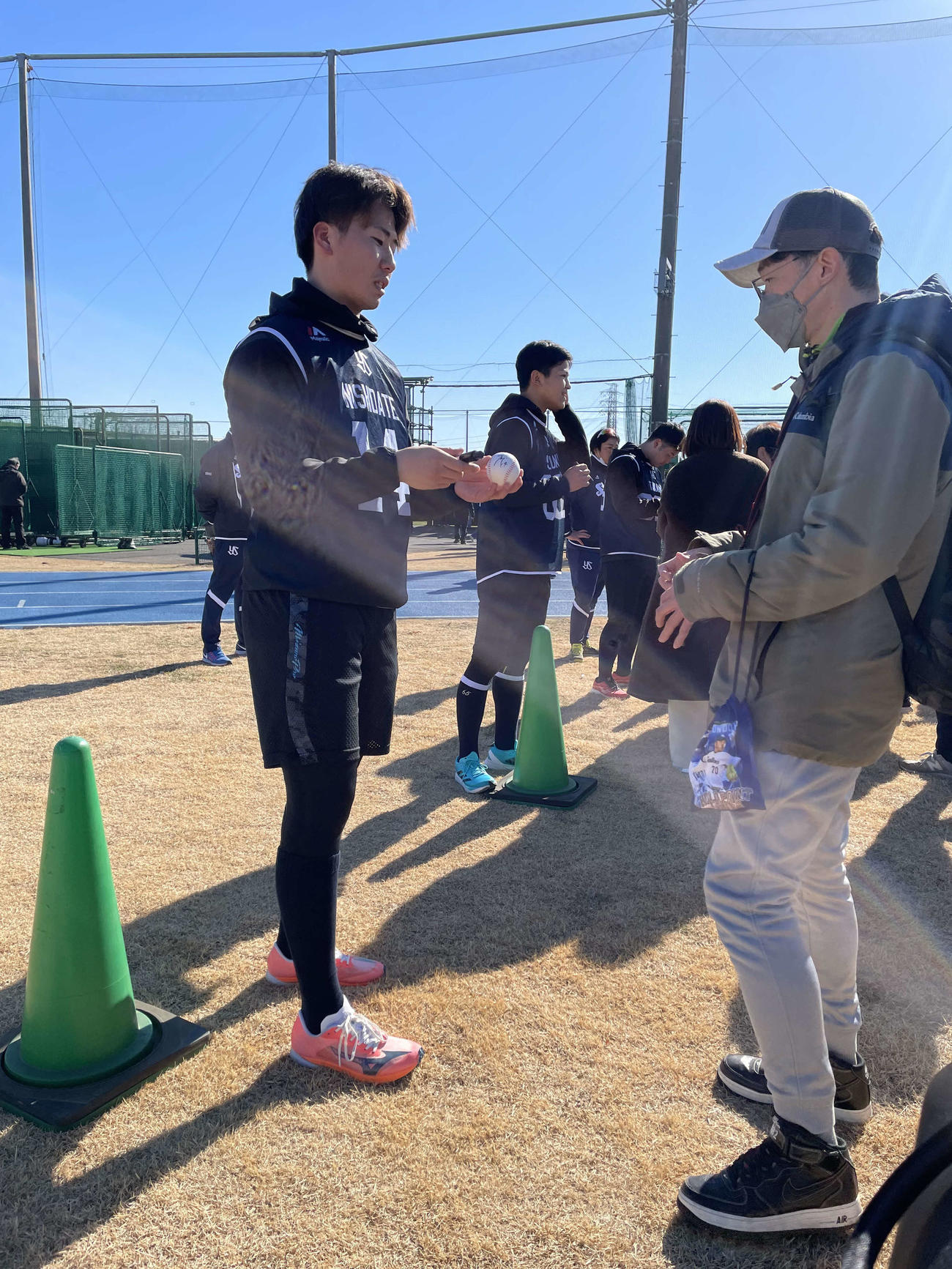 練習後にファンへサインを書くヤクルトのドラフト1位西舘昂汰投手（22＝専大、手前）