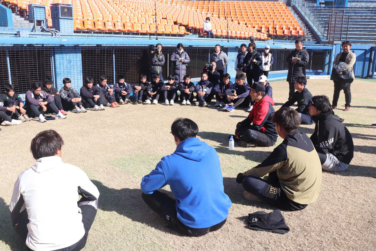 自主トレ体験会で中学生らへの質問会を行う阪神岩崎優投手（円の中心、赤色のジャージ）ら阪神投手陣（撮影・波部俊之介）