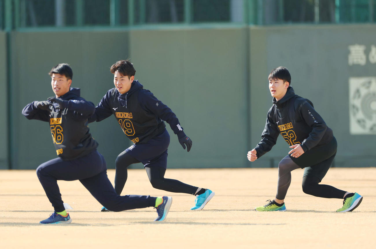 新人合同自主トレでウオーミングアップする、左から阪神百崎、下村、山田＝2024年1月13日、鳴尾浜球場