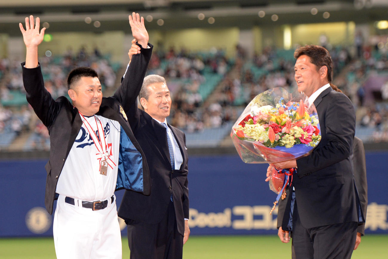 試合前、2000本安打を達成した谷繁（左）は、山田久志氏から名球会ブレザーを着させてもらいファンの声援に応える。右は佐々木主浩氏（2013年5月撮影）