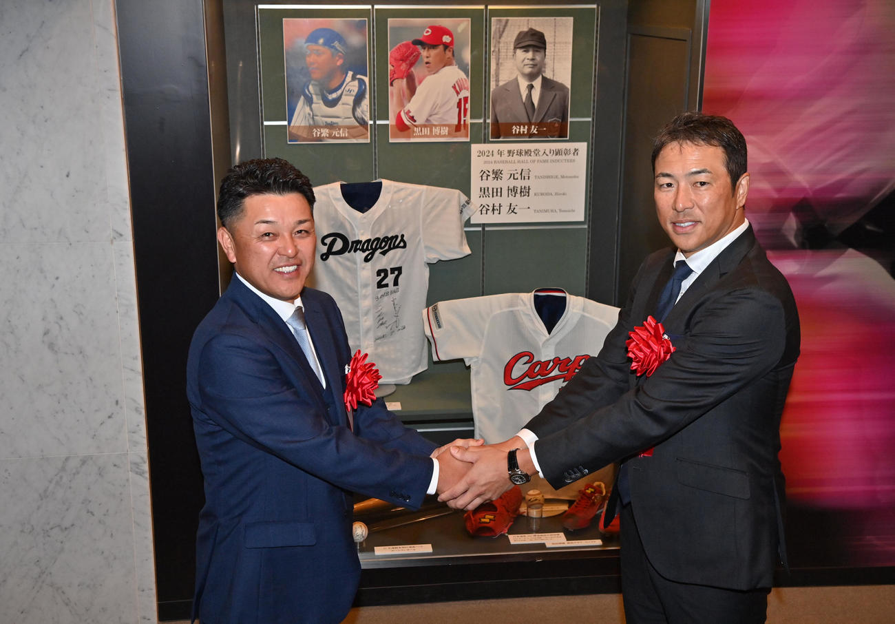 野球殿堂入り記念展示の前で握手する谷繁氏（左）と黒田氏（代表撮影）