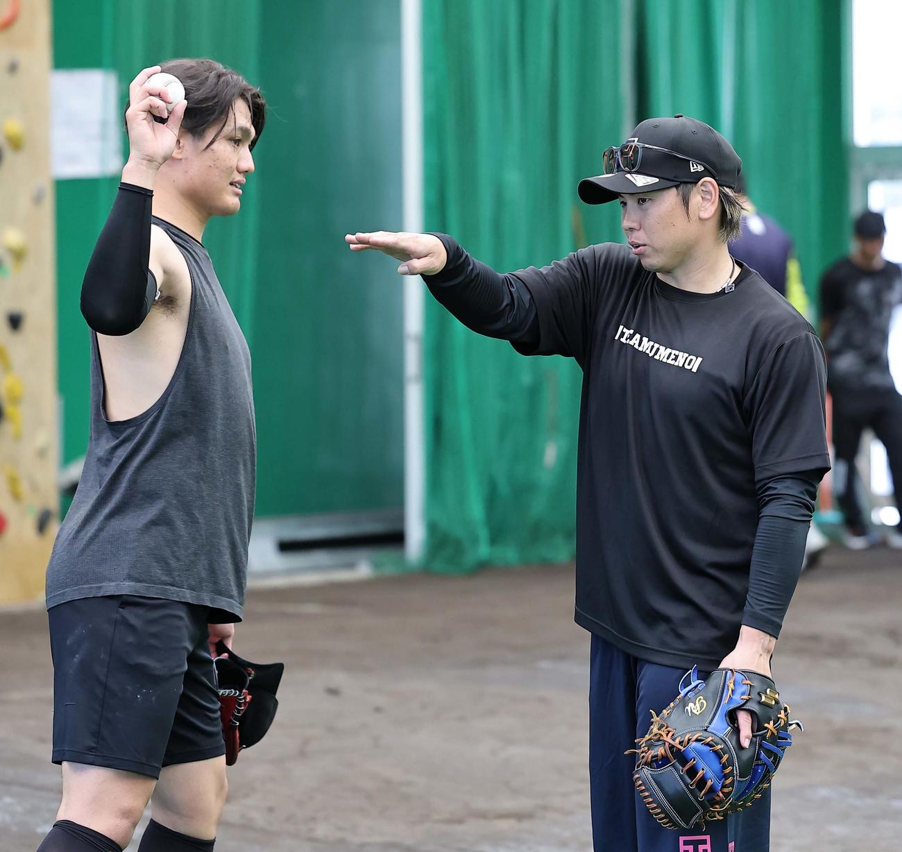 ブルペンでの投球練習を終えた西純（左）にアドバイスを送る梅野（撮影・上田博志）