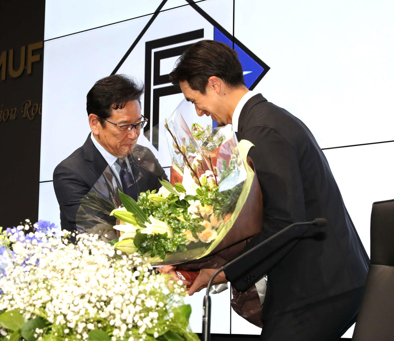 レイズへの移籍会見で同期入団の日本ハム栗山CBO（左）から花束を受け取る上沢（撮影・黒川智章）