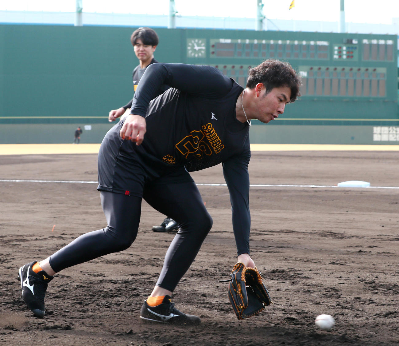 新人合同自主トレでノックを受ける阪神椎葉。奥は石黒（撮影・上山淳一）