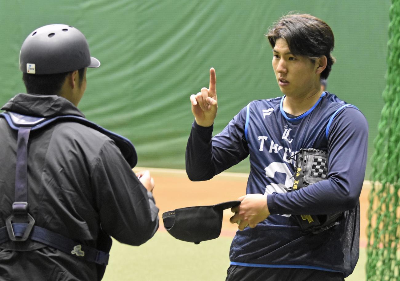 投球練習後、ブルペン捕手と話し込む西武武内（右）（共同）