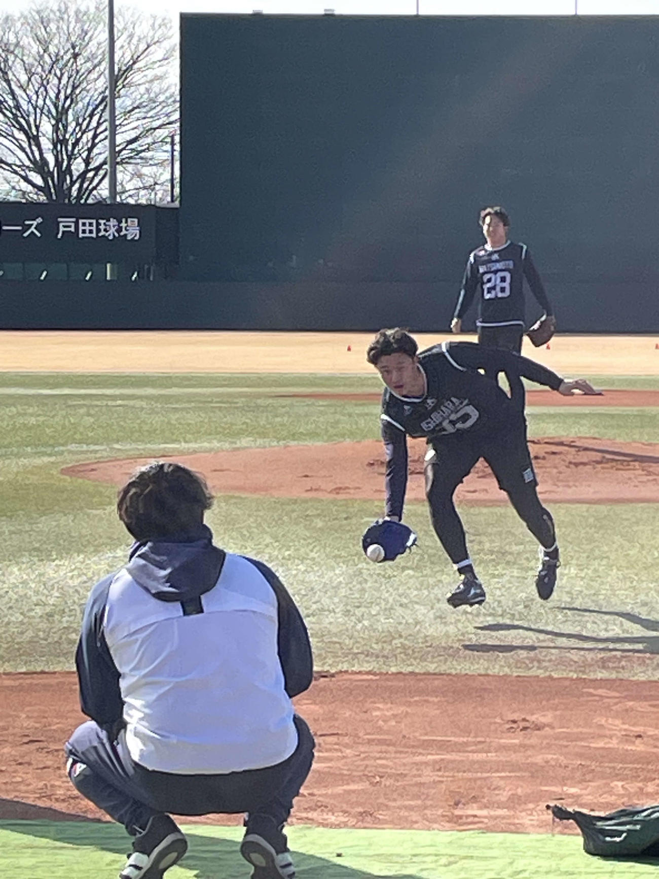 守備練習でトスするヤクルトのドラフト3位の石原、後方はドラフト2位松本