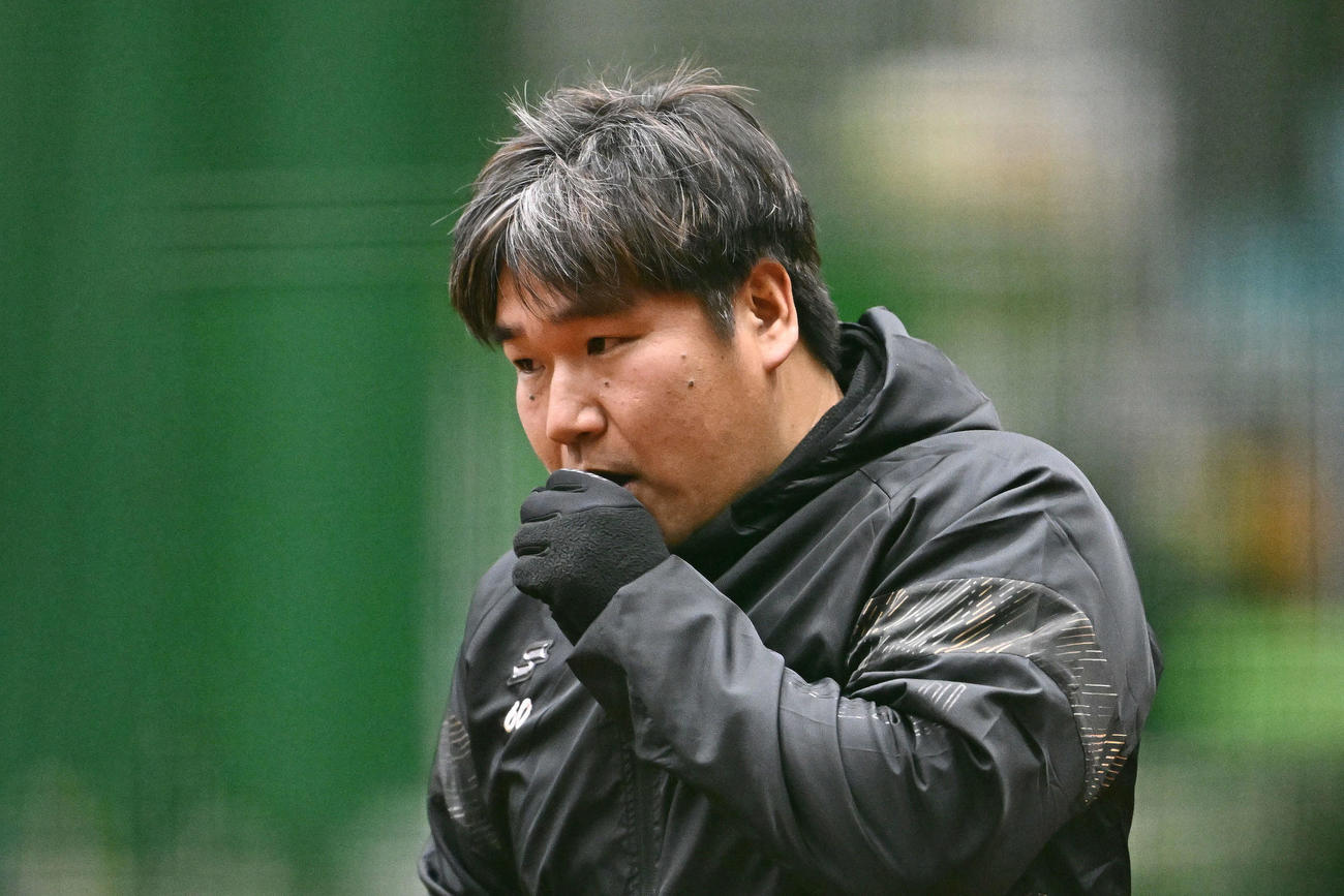 寒さでかじかむ手に息を吹きかけ温める西武中村剛（撮影・滝沢徹郎）