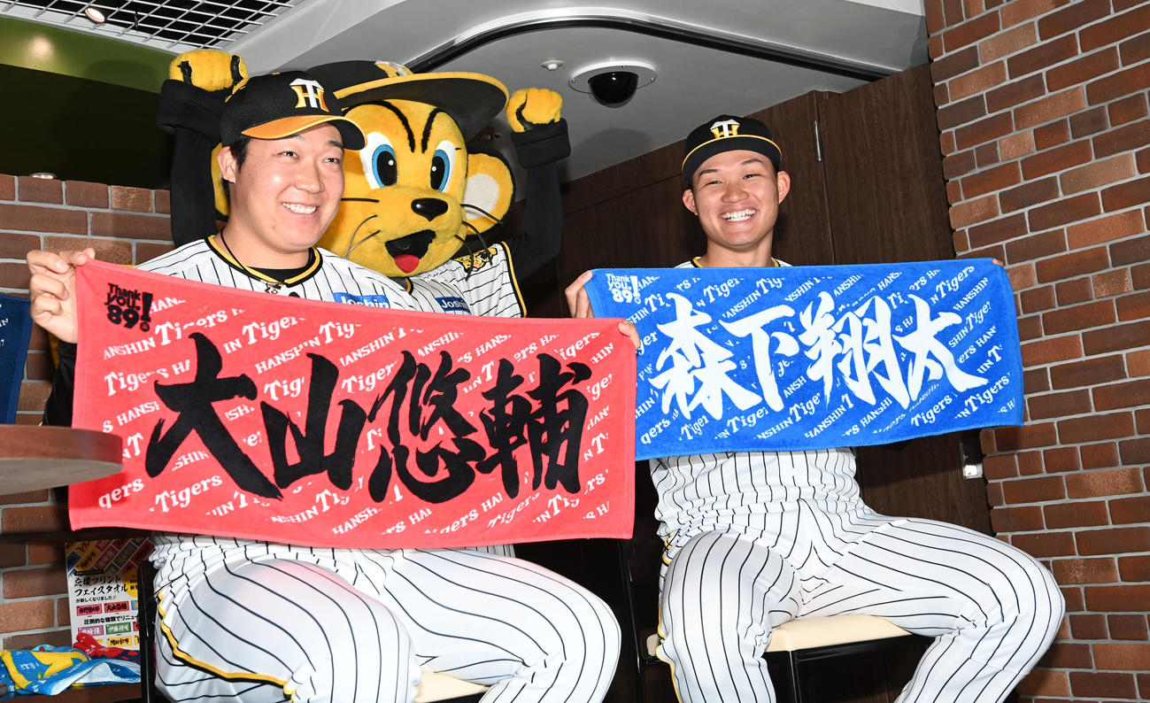 「2024新作グッズ内覧会」に出席、自身の「応援プリントフェイスタオル」を披露する阪神大山（左）と森下（撮影・前岡正明）