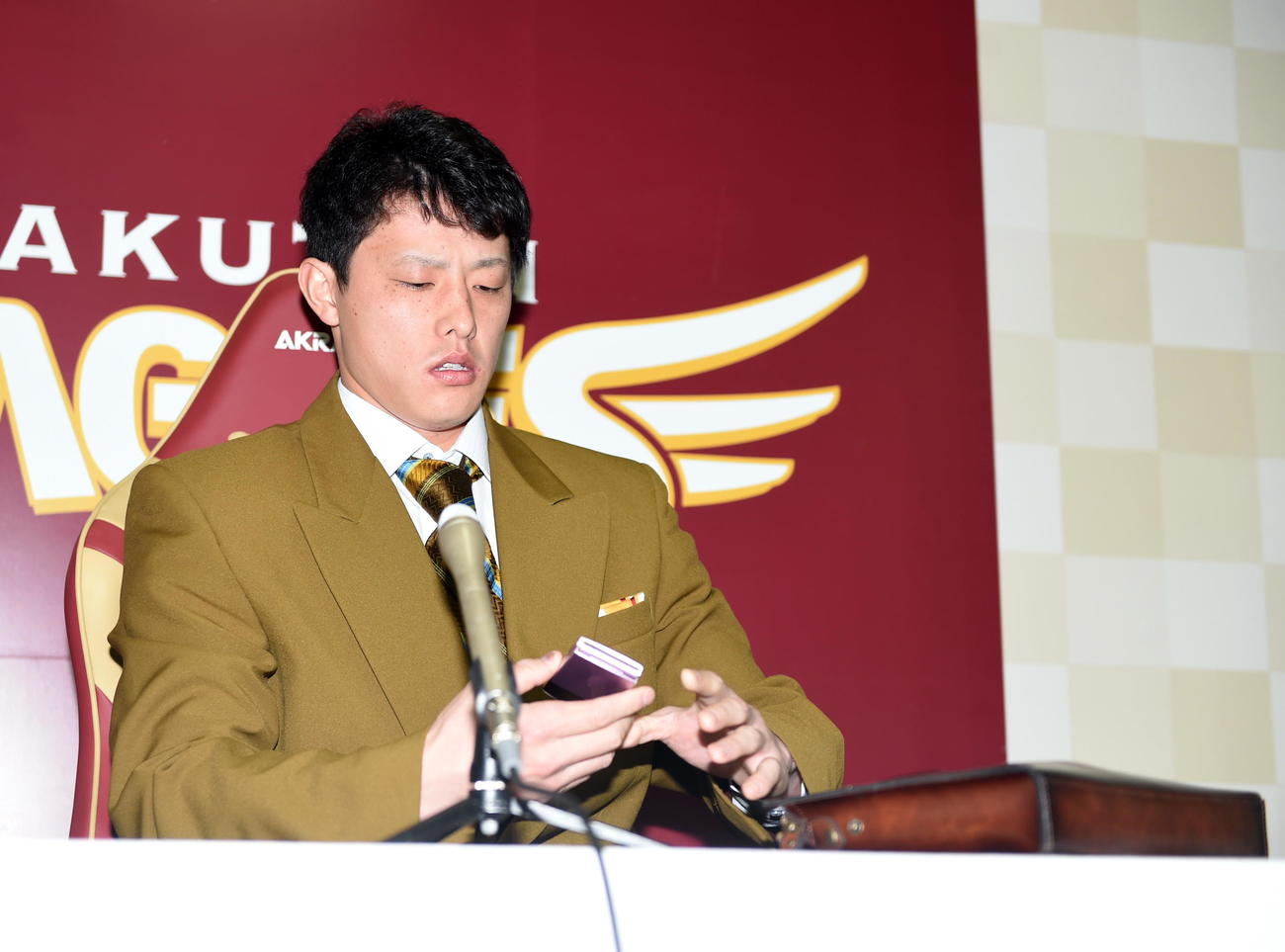 クラッチバッグからガラケーを取り出す楽天辰己（撮影・山田愛斗）