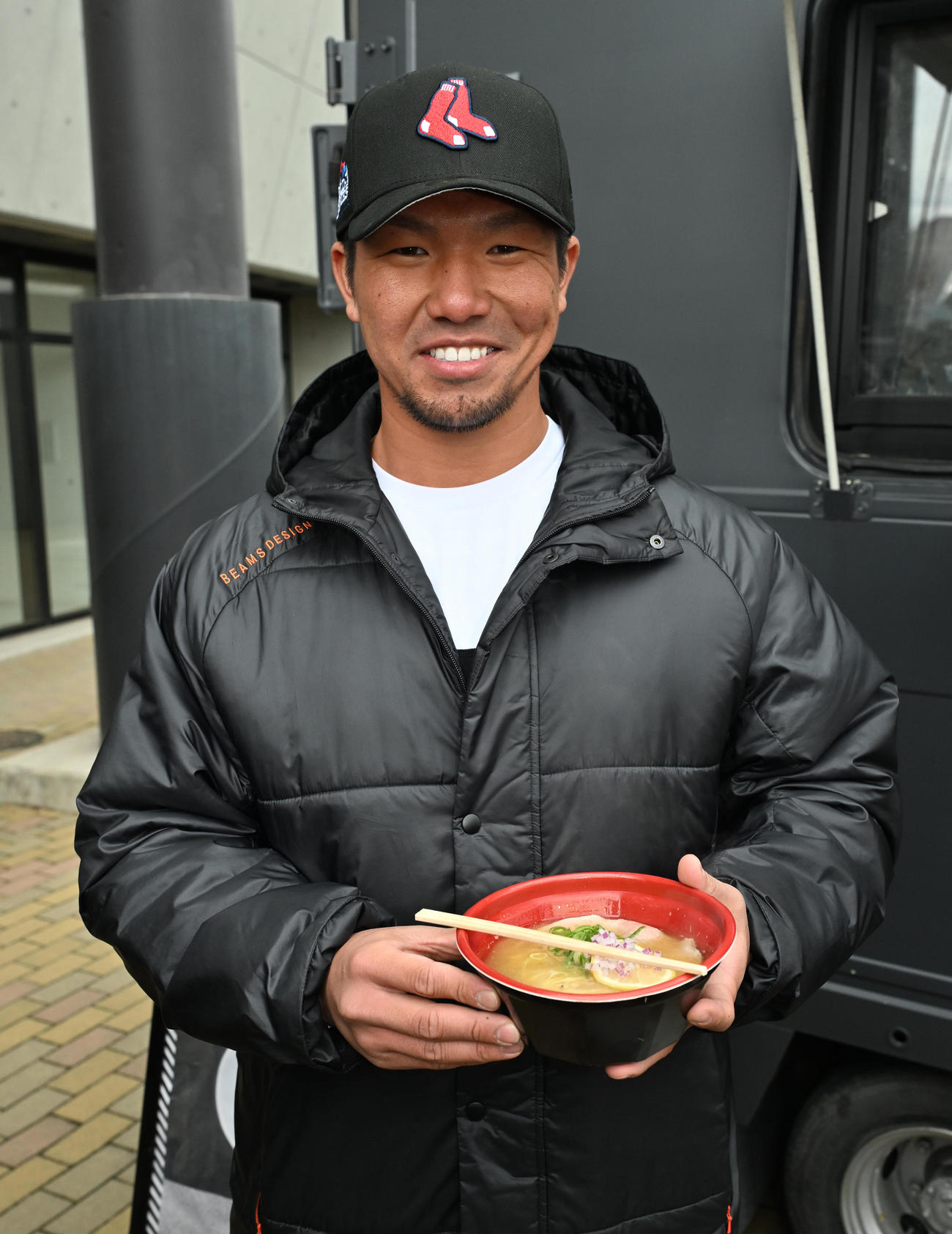 差し入れのラーメンを手に笑顔を見せる頓宮（撮影・石井愛子）